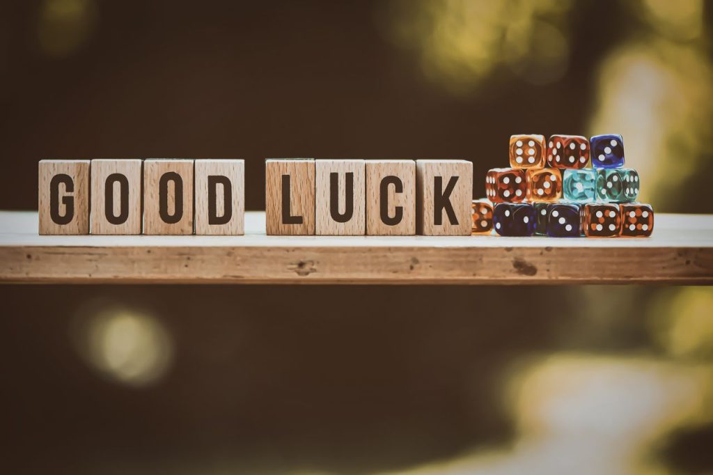 Wooden blocks spelling Good Luck with colorful dice on a wooden surface.